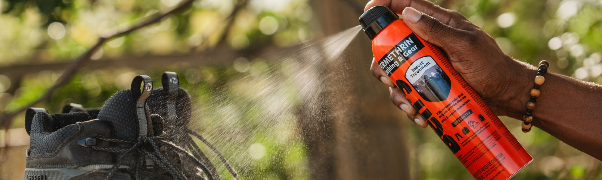 Spraying Ben's Clothing and Gear on shoes outside