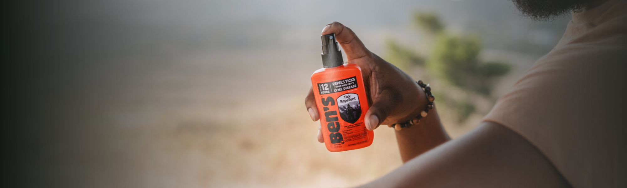 Man spraying Ben's Tick Repellent on arm