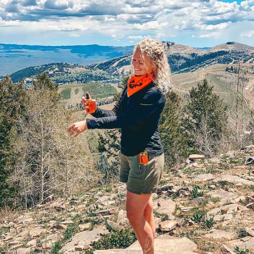 Ben's Tick & Insect Repellent Bandana with Insect Shield woman wearing while using repellent