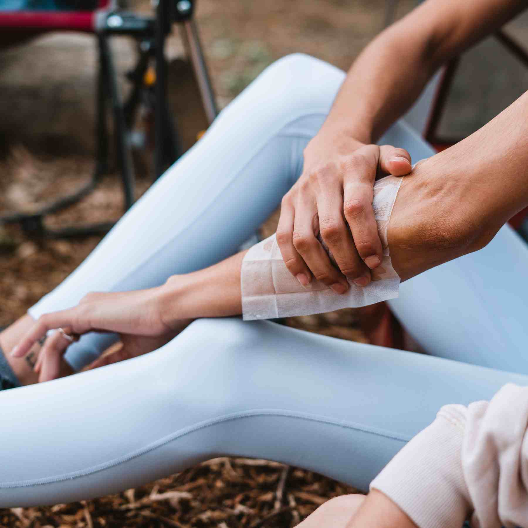 Woman applying Ben's 30 DEET Wipe to arm in blue leggings while camping