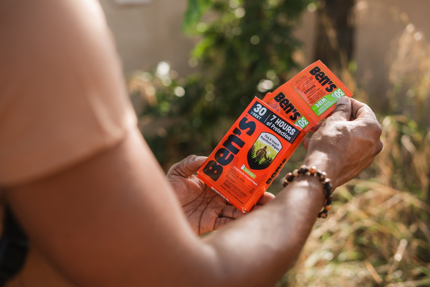 A woman's hands taking Ben's insect repellent wipes out of the package