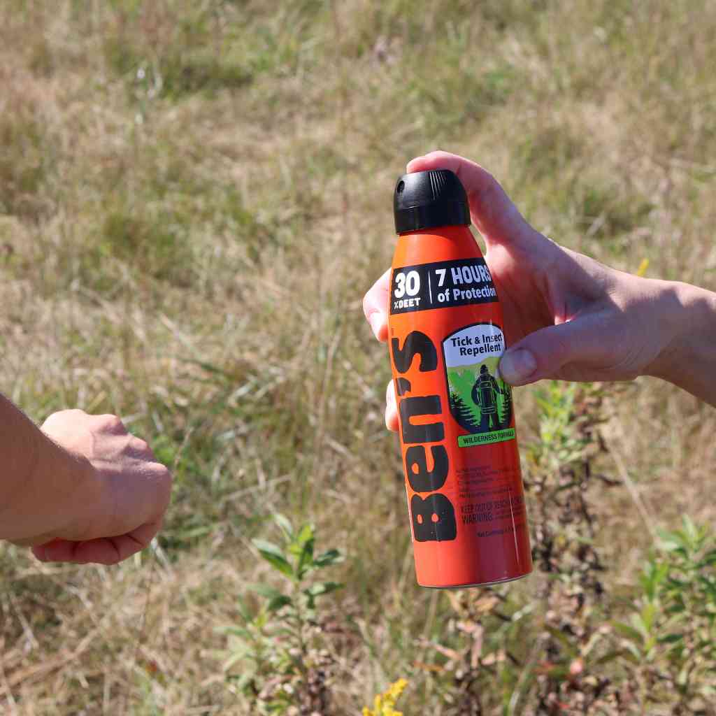 Ben's 30 Tick & Insect Repellent 6 oz. Eco-Spray person spraying on friend's arm in front of grass
