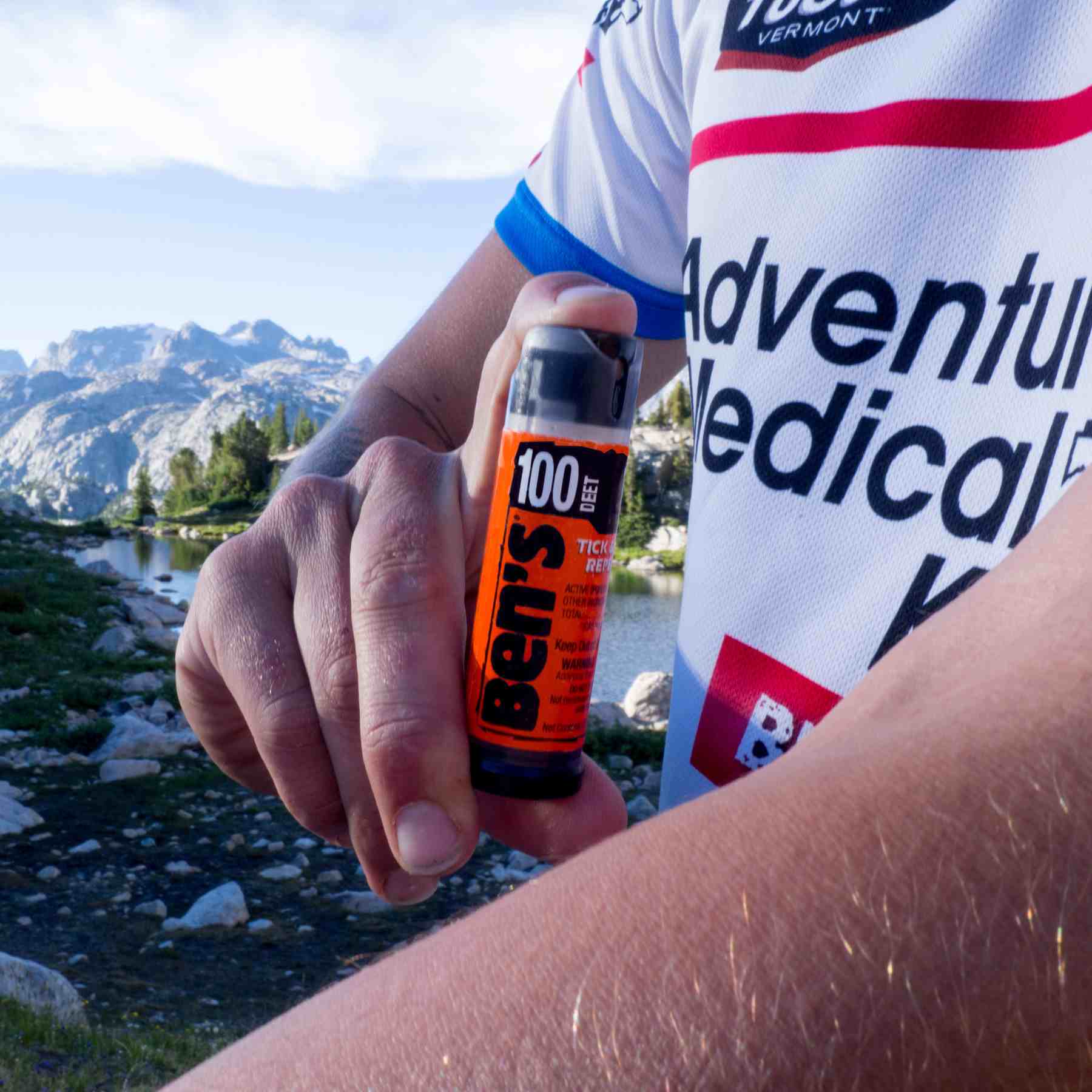 Ben's 100 .5 oz repellent being sprayed on arm in front of mountains